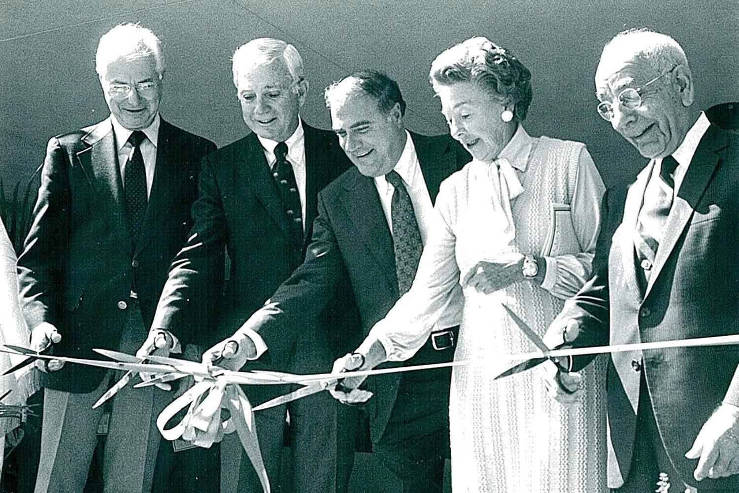 A ribbon-cutting featuring four men in suits and one woman in a dress at UCSF Fresno in 1981 (black and white photo)