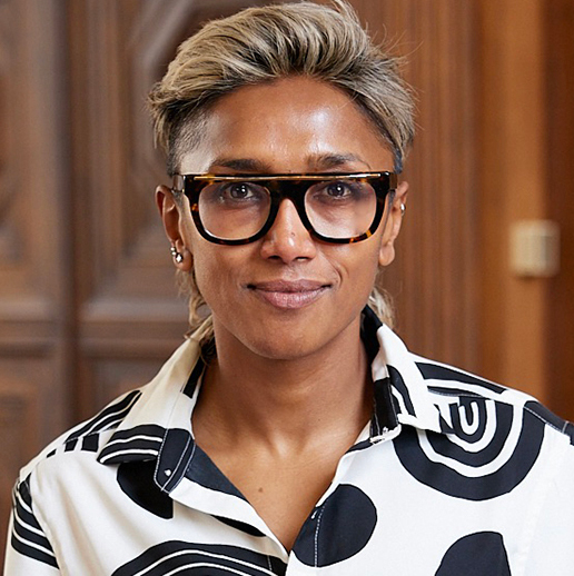 Woman with a swirly blouse glasses and blonde short hair