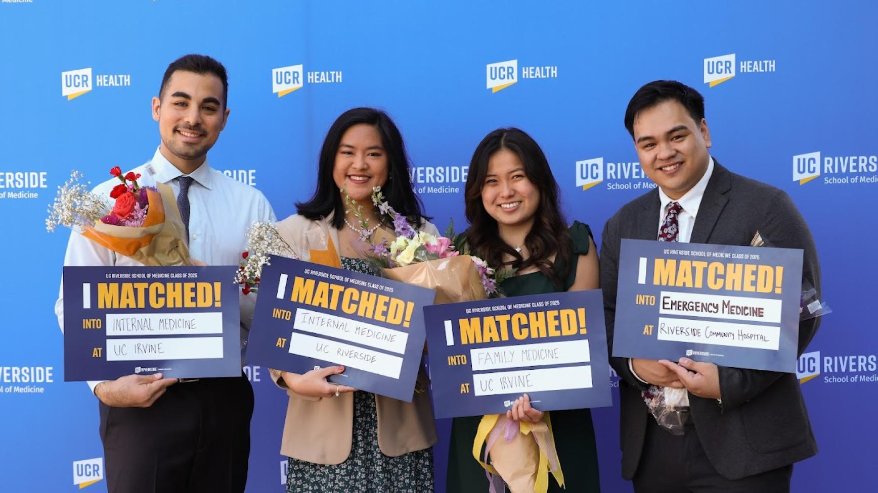 Four students hold up signs showing where they matched at UC Riverside's Match Day