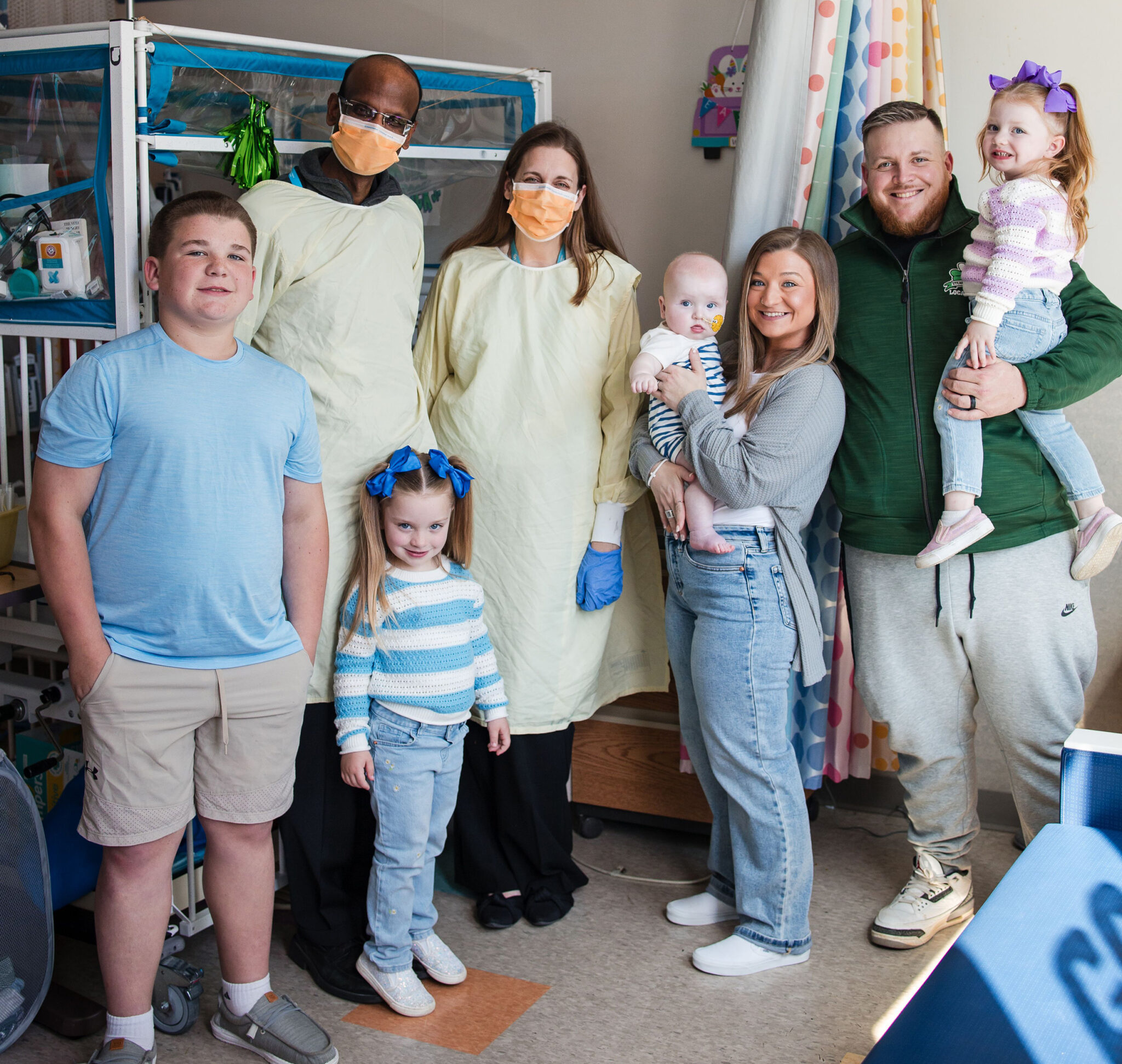 A family of six with two doctors pose after treatment at the hospital