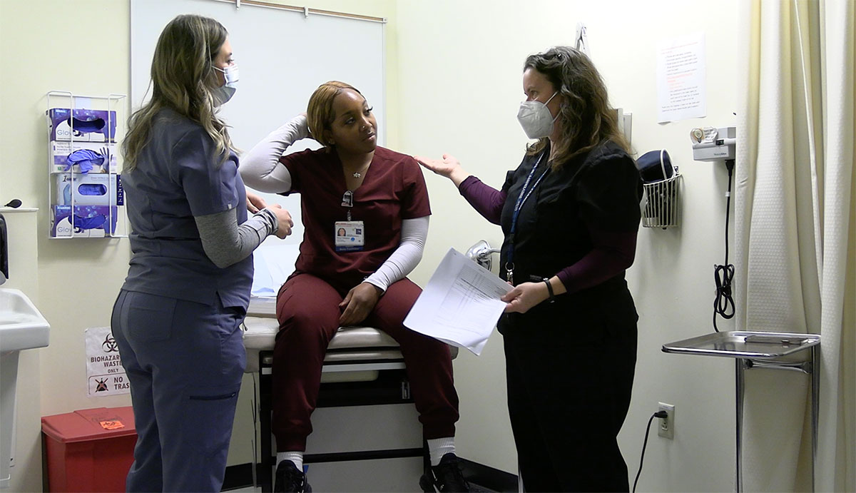 Bridget Gramkowski in a clinical room with 2 nursing students.