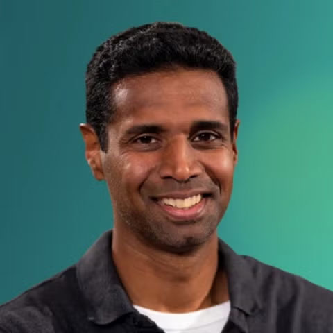 Chetan Nayak smiles at the camera against a gradient teal blue background.