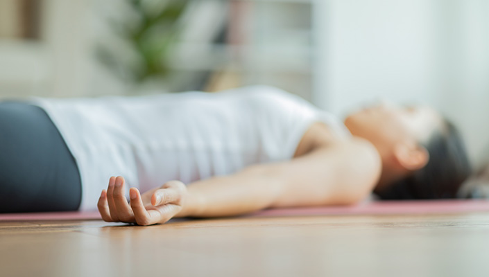 A woman lying down on a mat on the ground in athleisure wear
