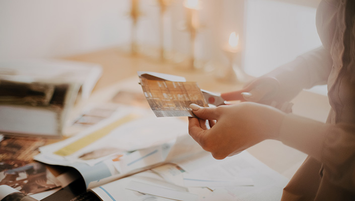 A person, here in focus as a pair of hands, cuts an image out of a magazine in soft light