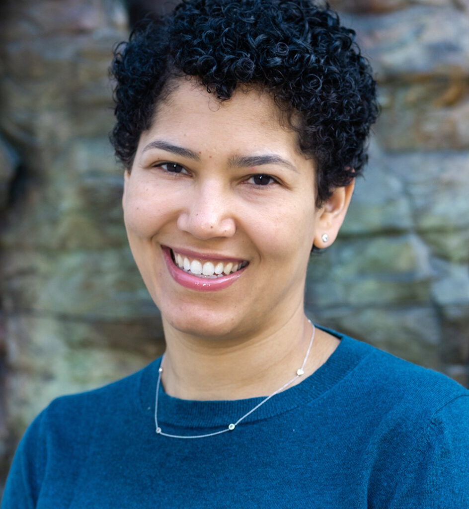Marika Landau-Wells smiles for a portrait wearing a dark blue top