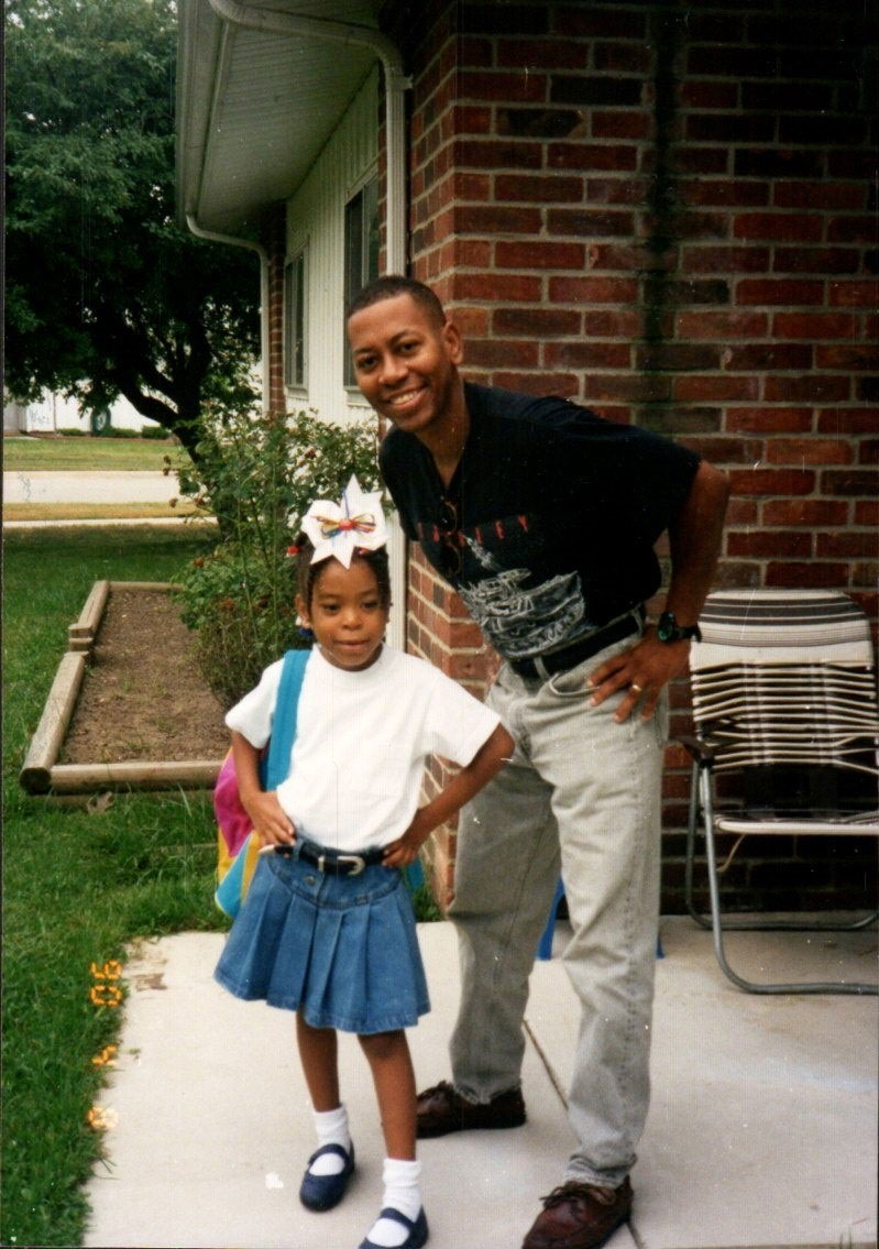 Mel Mann and his daughter Patrice, about age 5, smile with their hands on their hips on the porch of their home