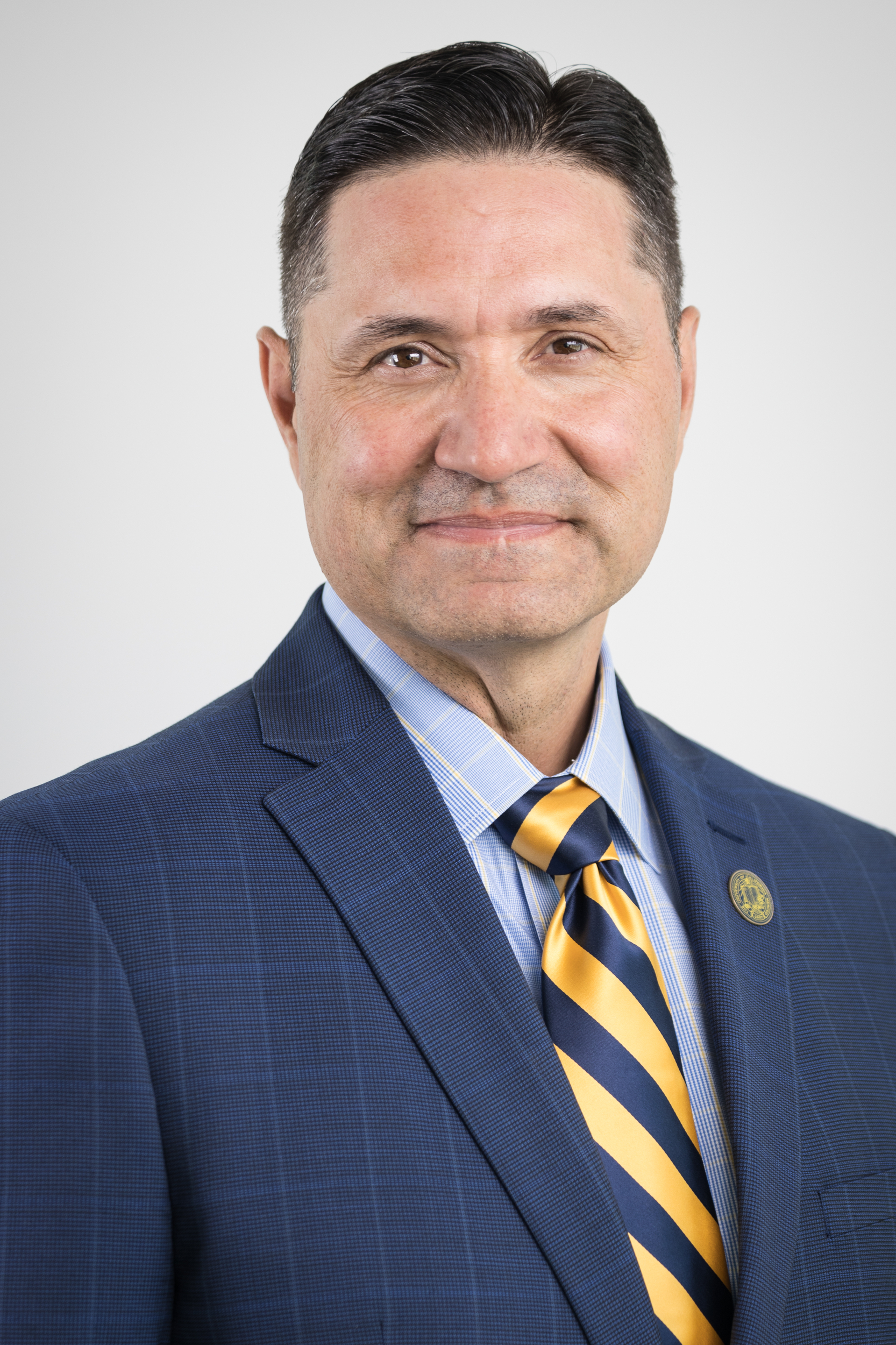 Chancellor Muñoz in a blue suit jacket and blue and yellow striped tie