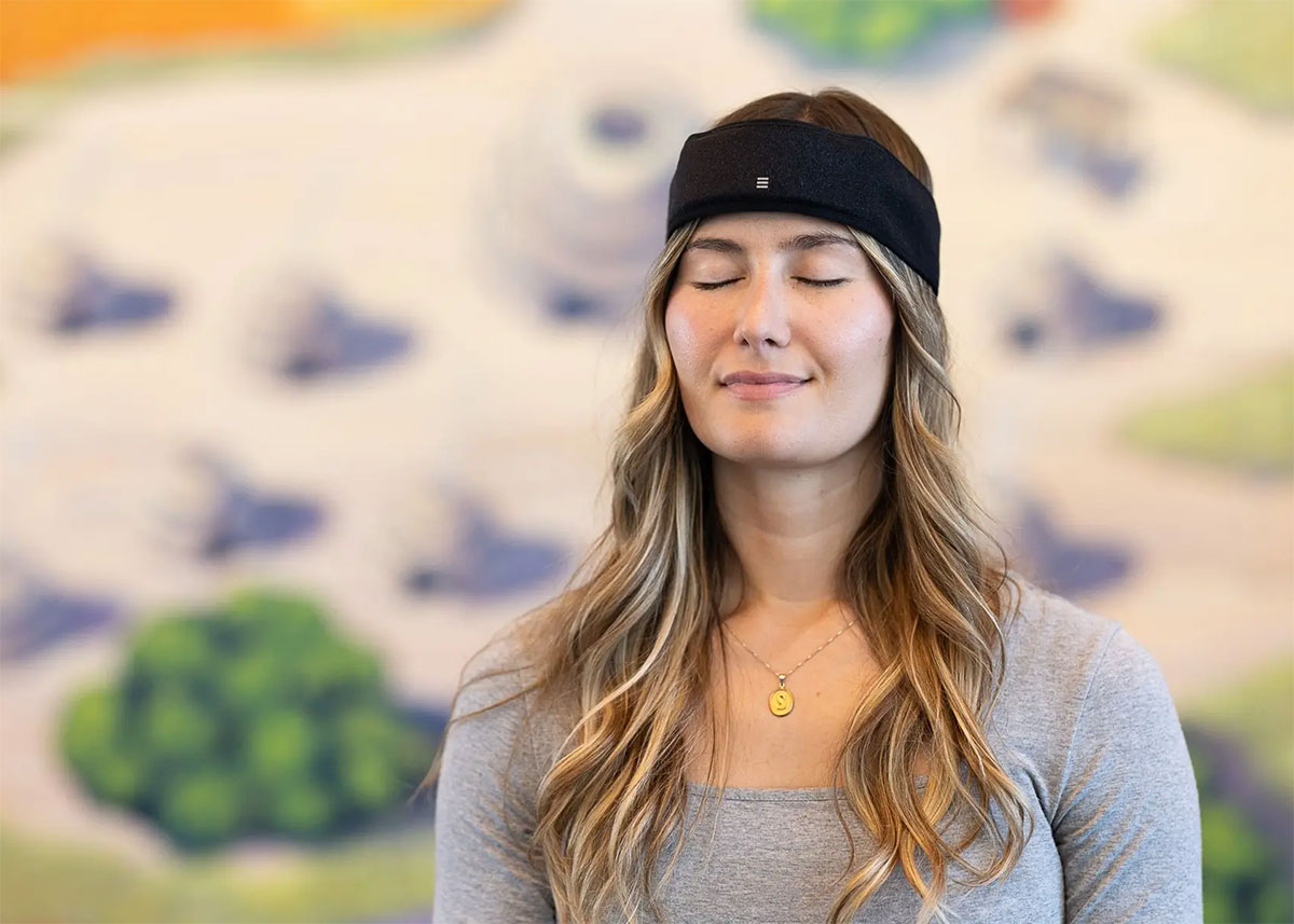 A woman with a placid expression closes her eyes while wearing a black headband.