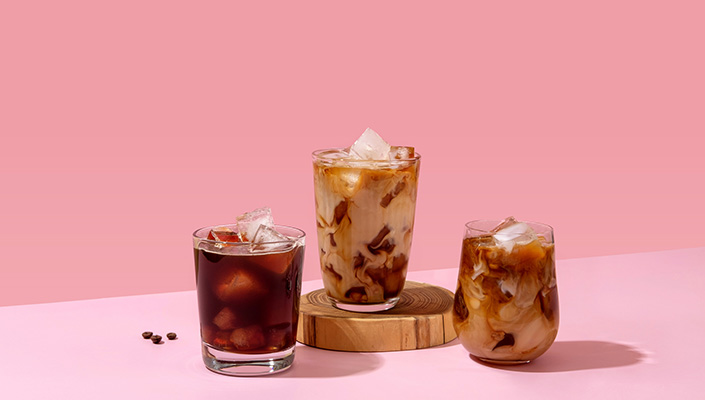 3 cups of ice coffee against a pink background