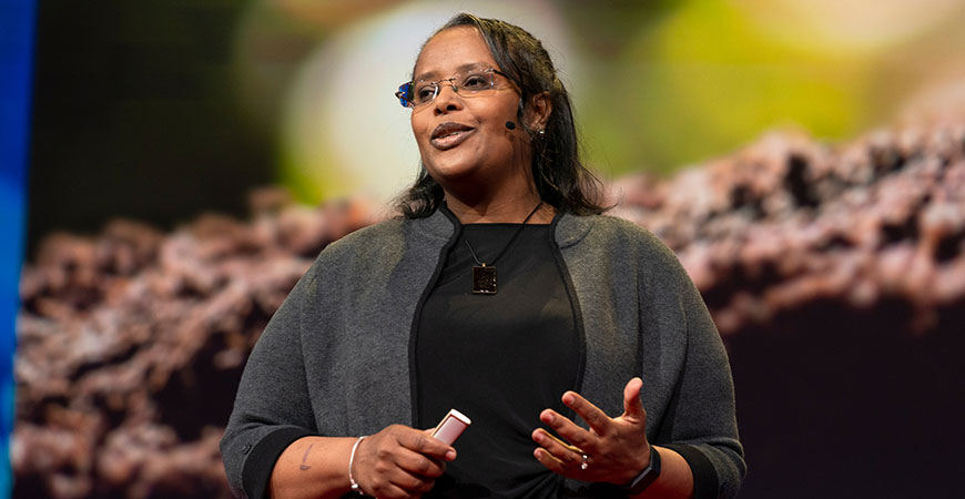 A woman giving a talk stands on a stage