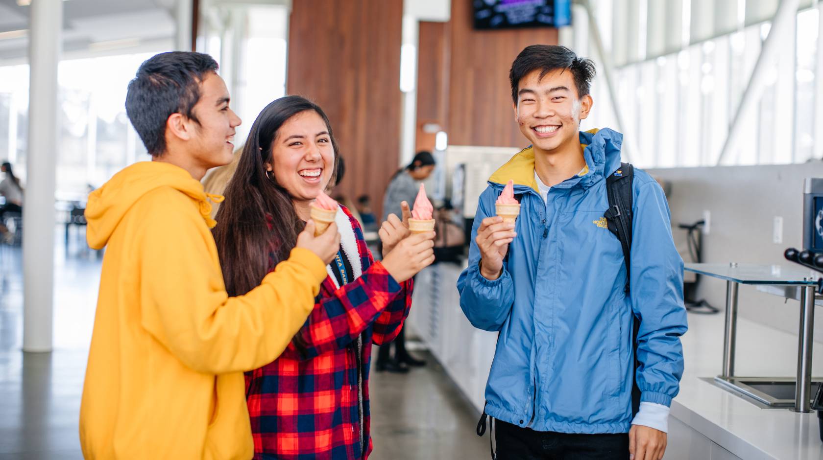 Three smiling students holding ice cream cones