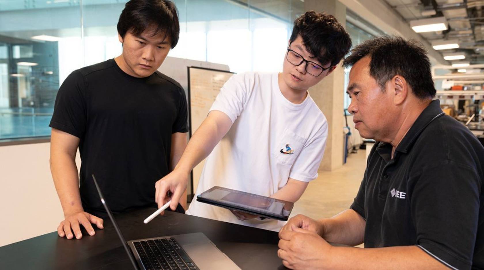 Two students and a professor look at a computer