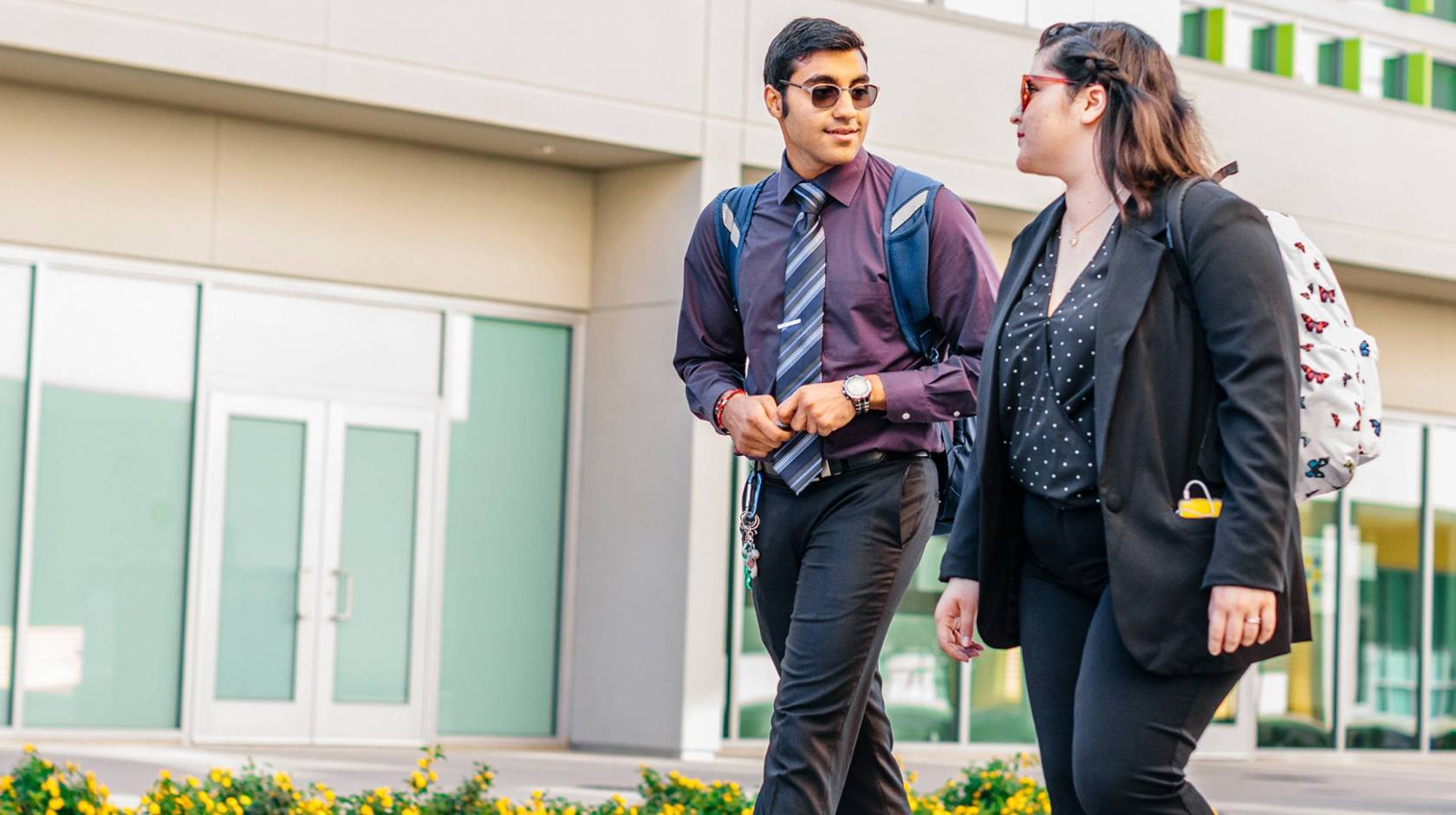 Two young people walk outside talking together in business casual clothing