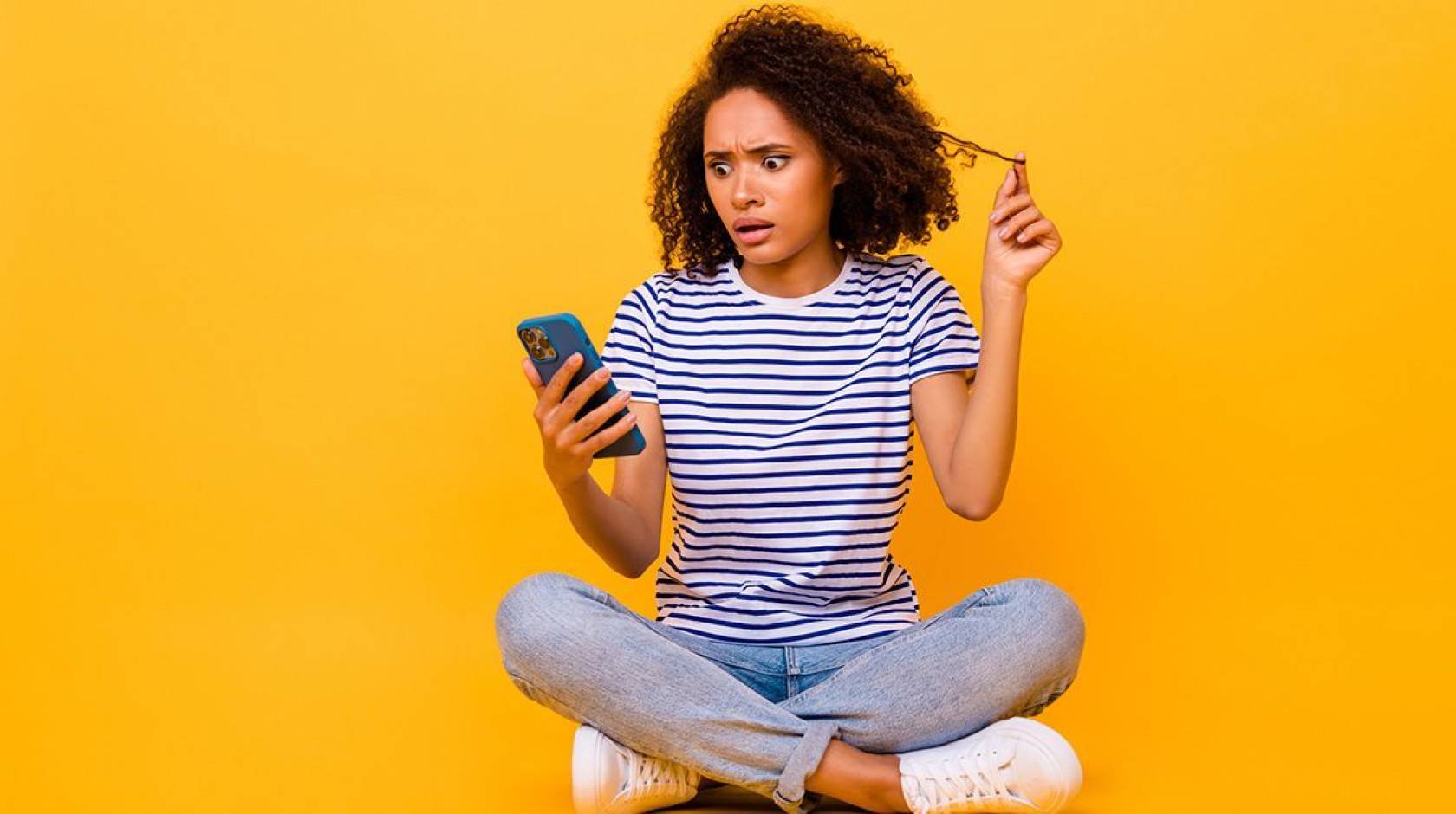 A woman looking at a smartphone with a shocked and worried expression
