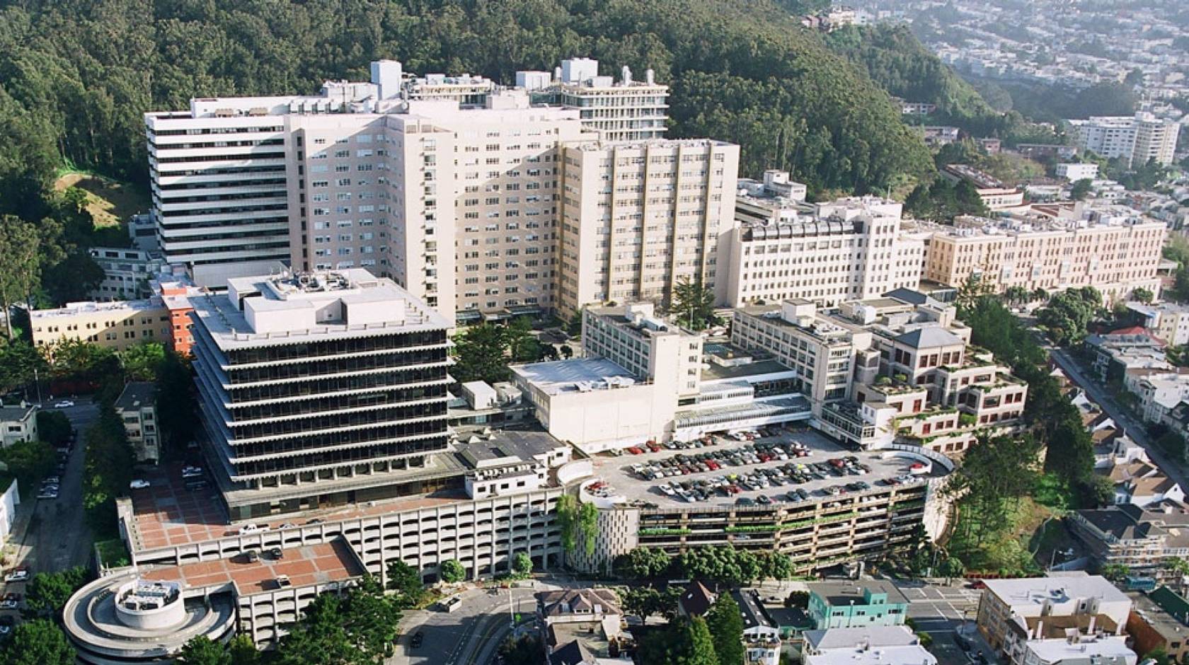 Aerial view of the UCSF Parnassus campus, white buildings at the base of a hill with trees