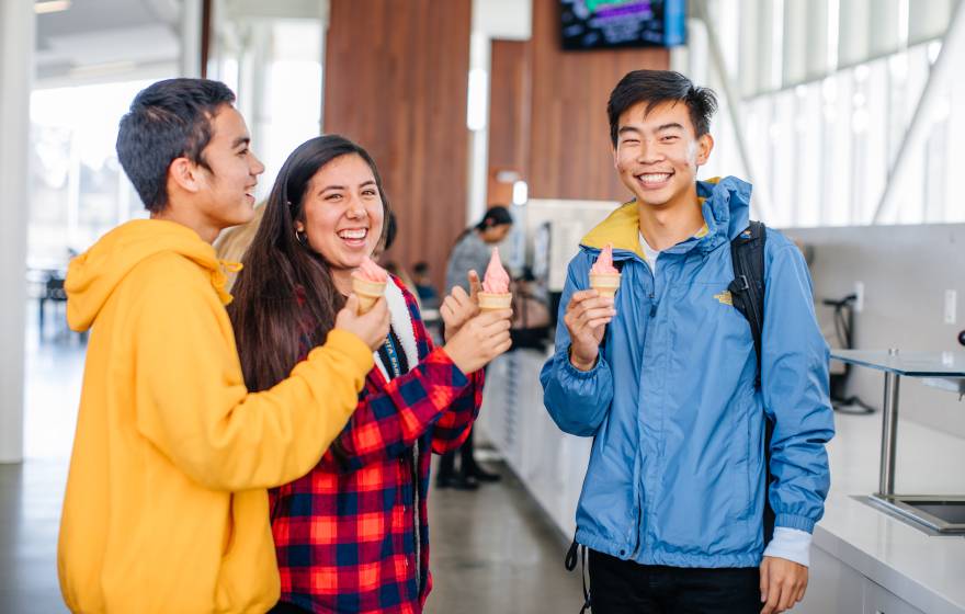 Three smiling students holding ice cream cones