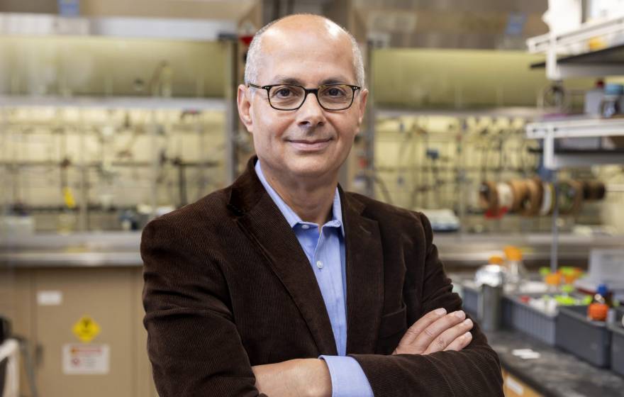 A man with glasses in a brown jacket smiles at the camera in a lab (Omar Yaghi)