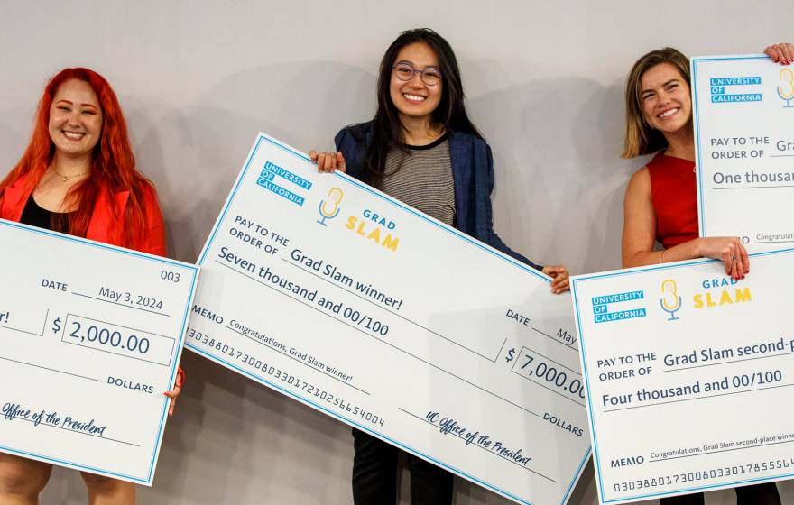 Three women posing with giant checks