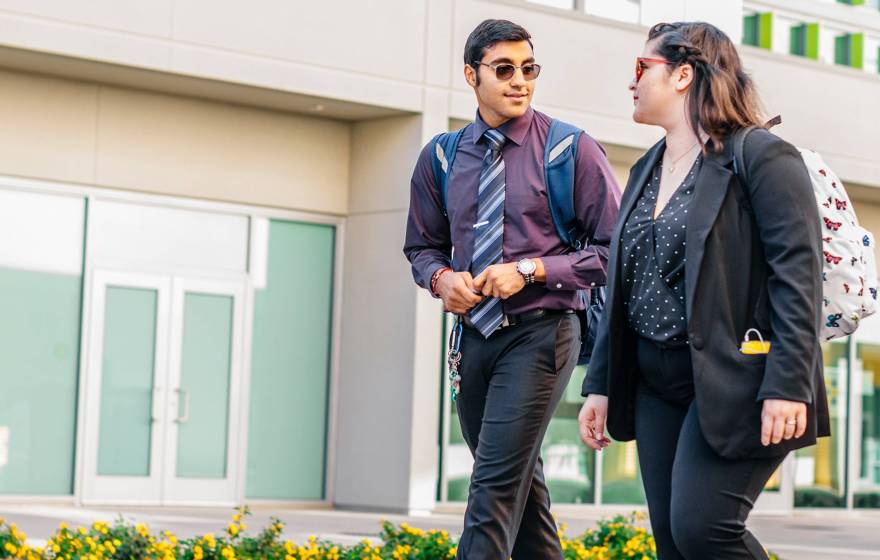 Two young people walk outside talking together in business casual clothing