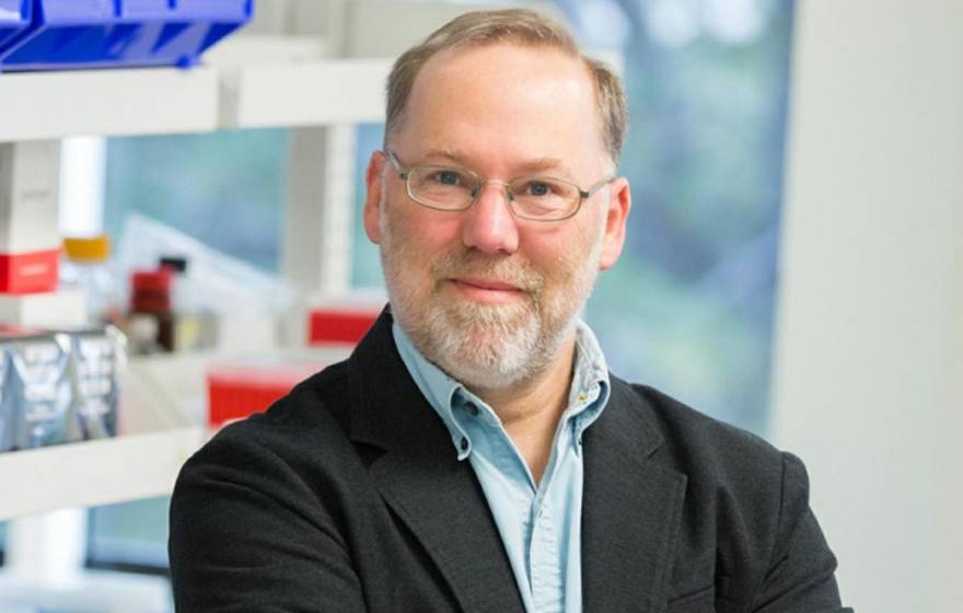 A man with a beard in glasses smiles in a lab