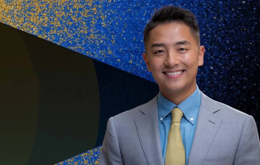 Young man in a suit smiling with John Wooden Leadership Fellows text on the left