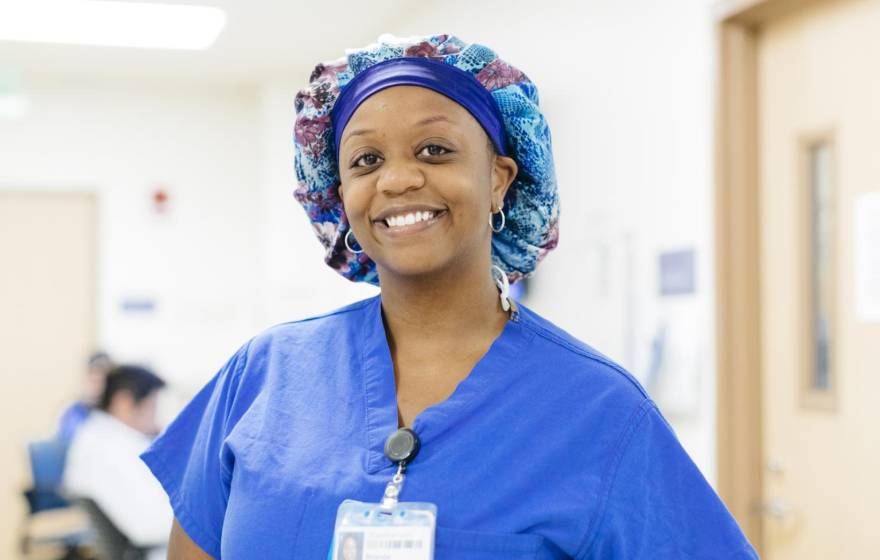 A nurse in scrubs and a hairnet smiles