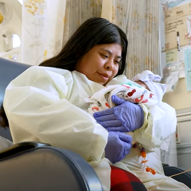 Jazmin Quijano sitting in a chair holding her baby at the hospital 