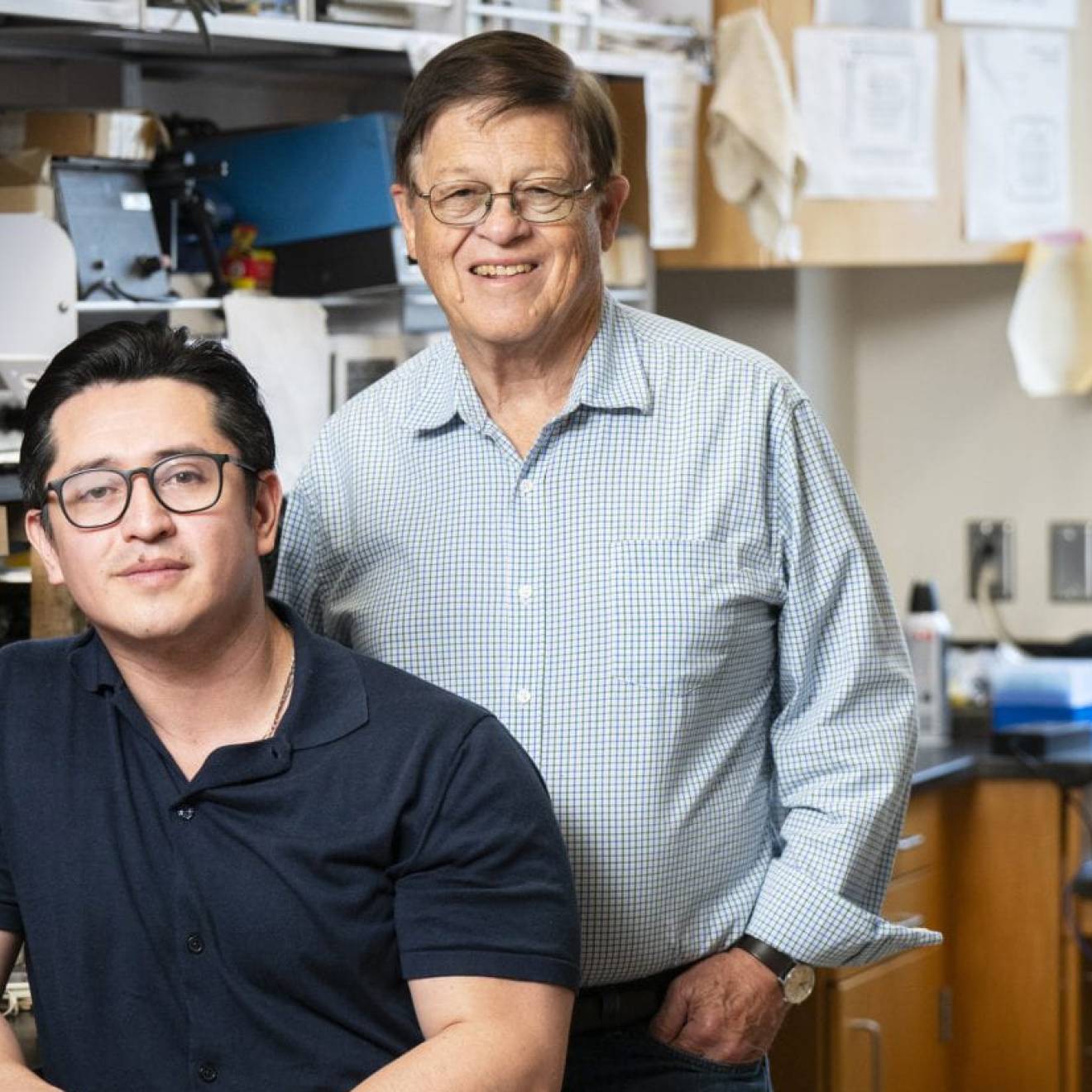 Two researchers wearing glasses posing in a lab