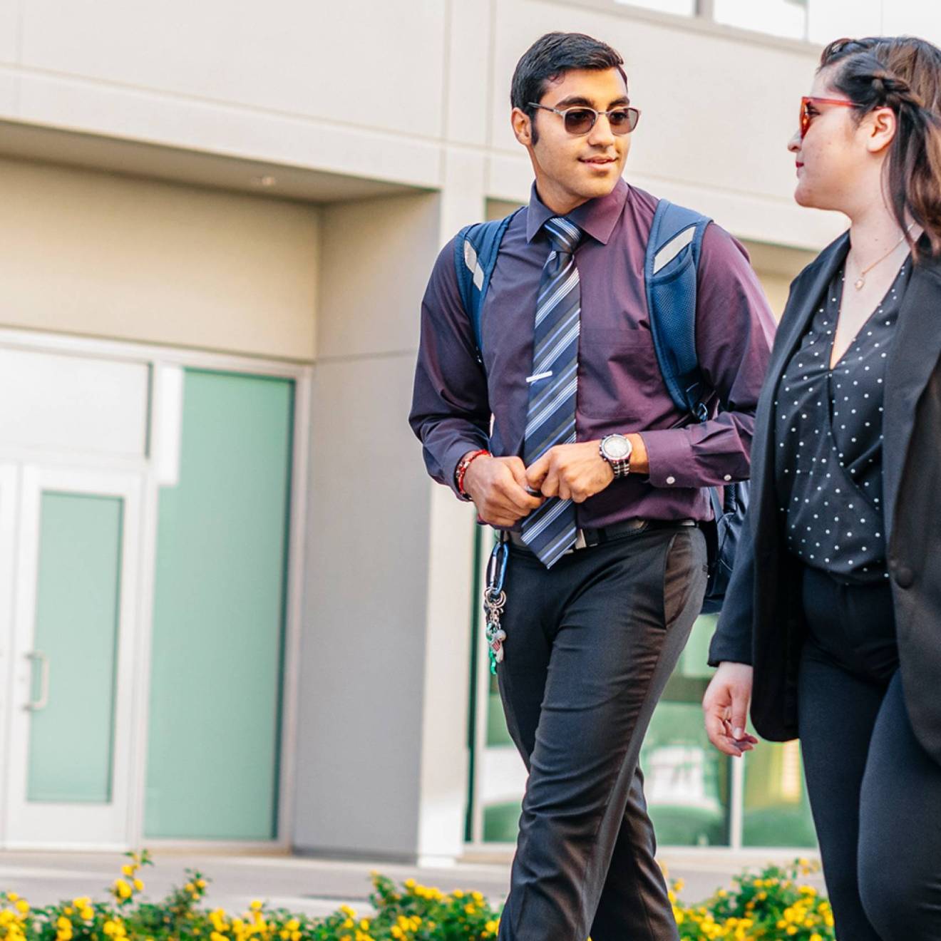Two young people walk outside talking together in business casual clothing