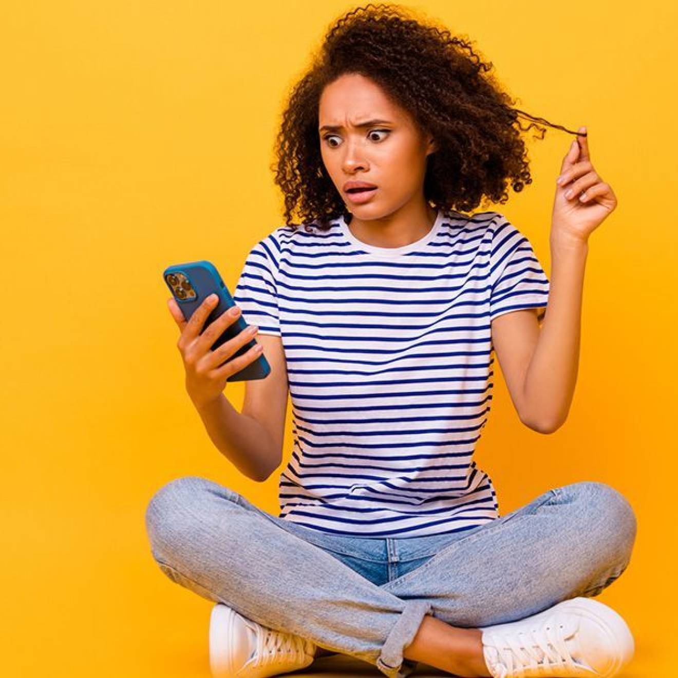 A woman looking at a smartphone with a shocked and worried expression