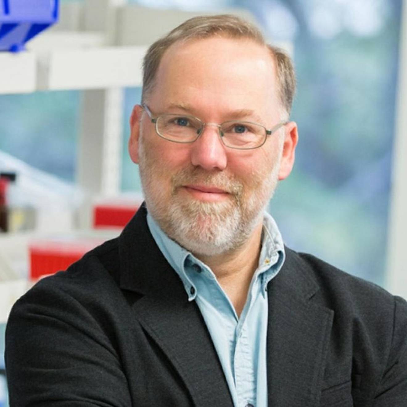 A man with a beard in glasses smiles in a lab