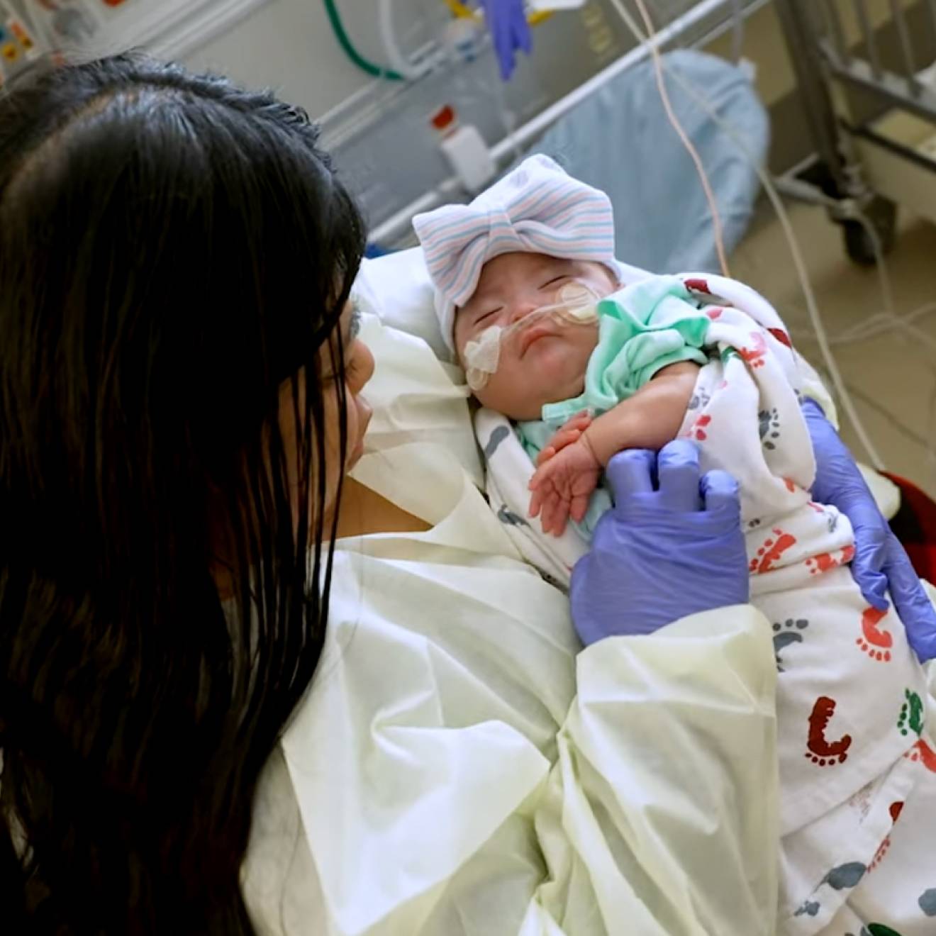 A young woman holds a young baby in her lap at a hospital