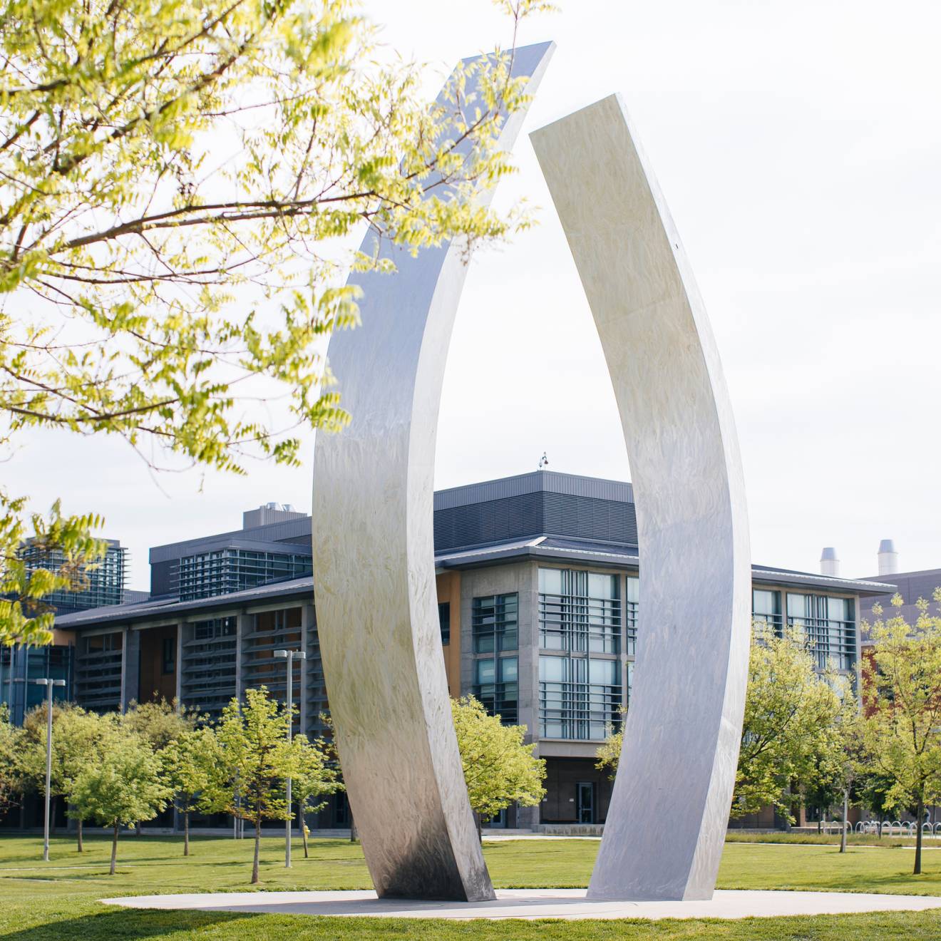 A view of UC Merced's campus with the sculpture, Beginnings, gently curving, vertical stainless steel arms, each about 40 feet high, in the center
