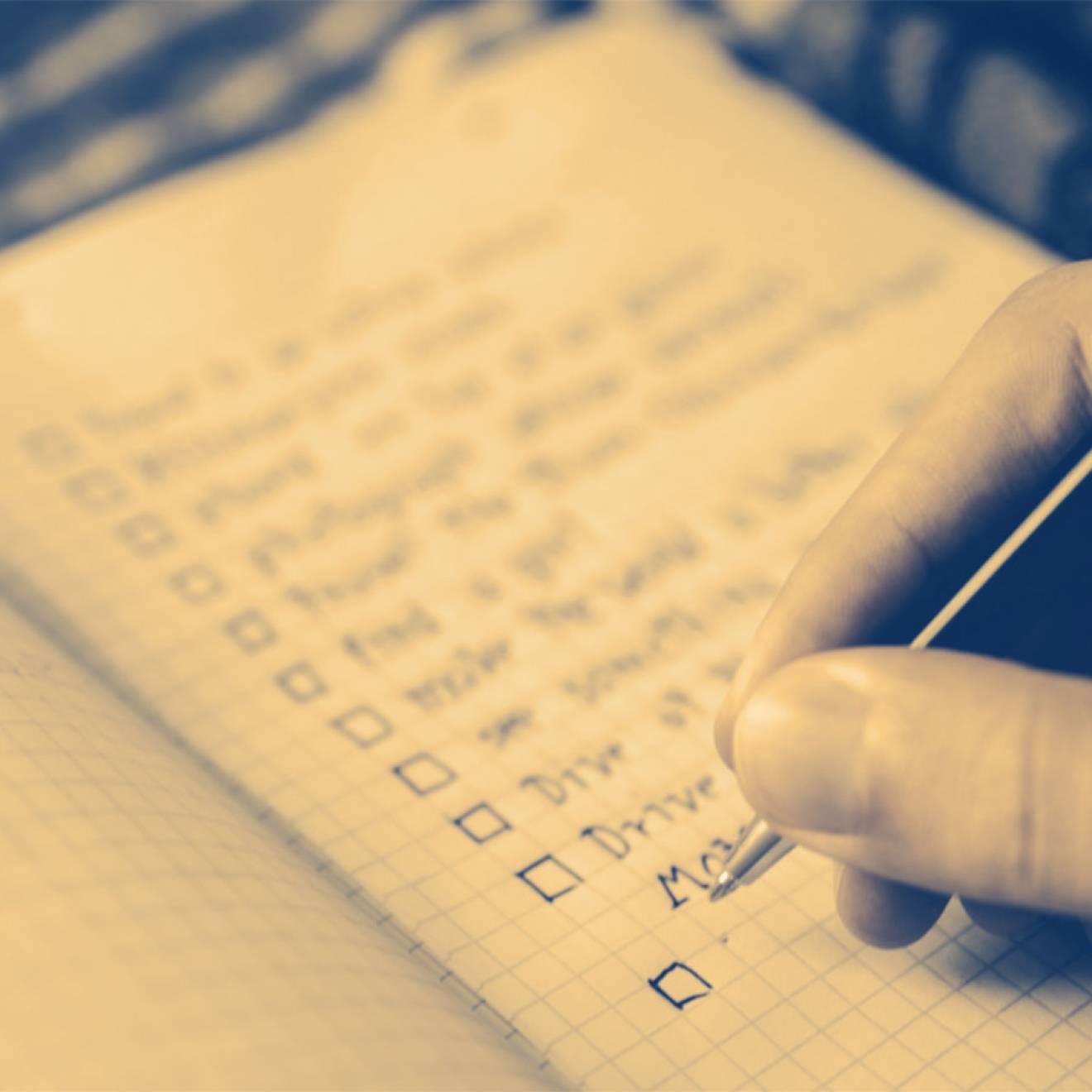 A sepia-toned close-up of a hand writing a to-do list with check-off boxes