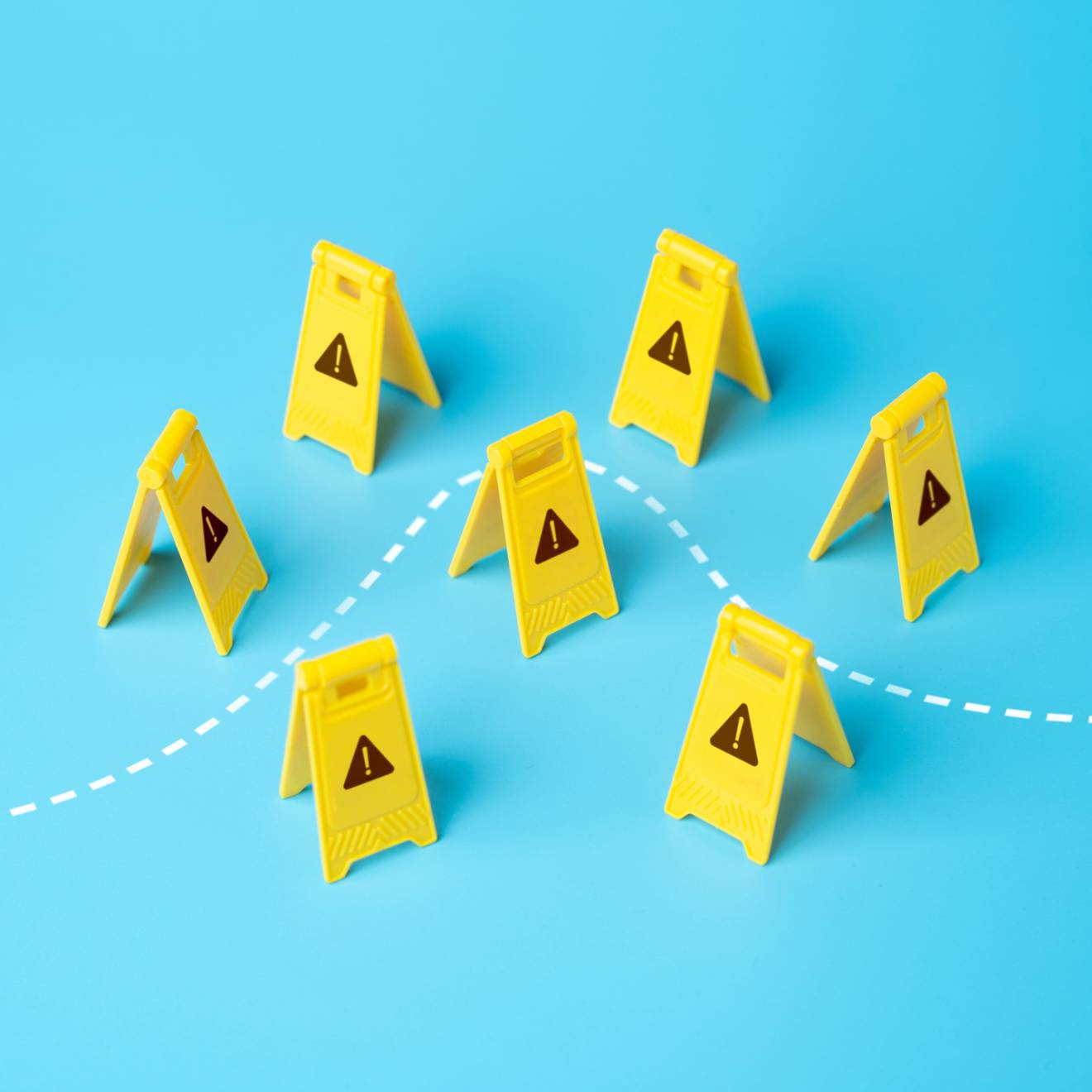 A set of childlike yellow construction warning signs with little warning signs on them with a dotted line going through, on a light blue background