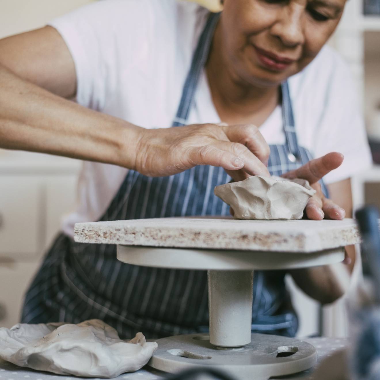 A person wearing an apron working at a ceramics wheel